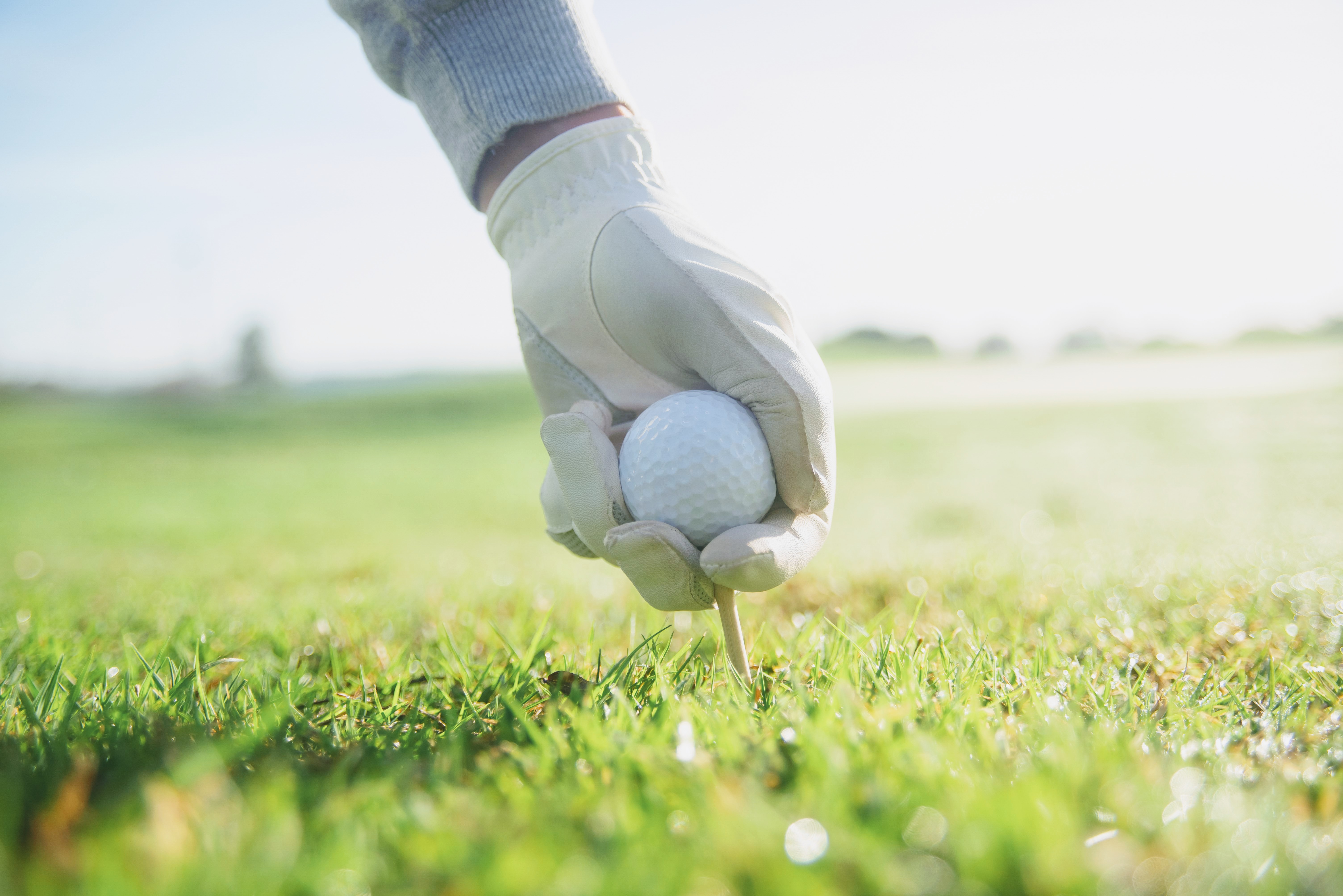 A golfer placing a ball on the tee at dawn